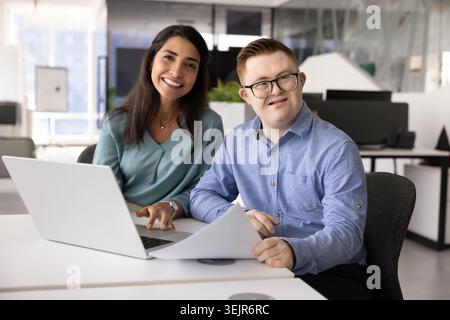 Porträt verschiedener Mitarbeiter, die am Schreibtisch mit Laptop sitzen Stockfoto