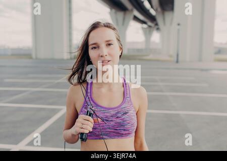 Junge Frau, die ein Sprungseil hält, nach dem Outdoor-Workout unter der Brücke Stockfoto