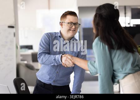 Kopfjäger beim Händeschütteln mit jungen männlichen Bewerbern mit Down-Syndrom Stockfoto