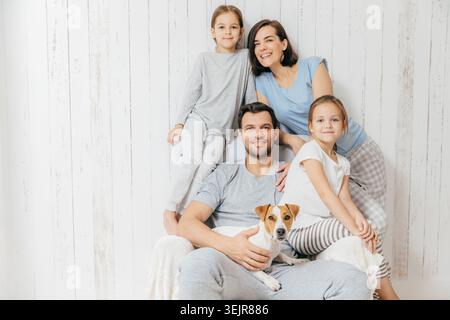Glückliche Familie mit zwei Töchtern und Hund, die zu Hause zusammen sitzen Porträt Stockfoto