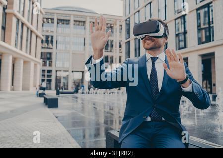 Geschäftsmann mit Virtual Reality-Headset im Freien im modernen Innenhof des Büros Stockfoto