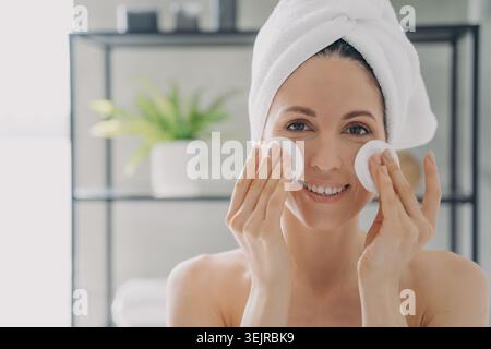 Frau reinigt Gesicht mit Wattepads im Badezimmer Nahaufnahme während der morgendlichen Hautpflege-Routine Stockfoto