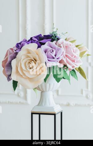 Blumenstrauß aus pastellfarbenem Papier in weißer Vase auf Sockel in eleganter, heller Inneneinrichtung Stockfoto