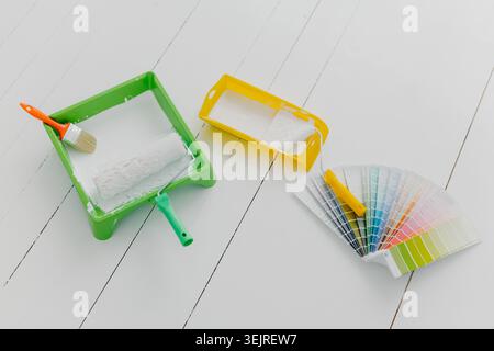 Malerwalzen Tabletts Pinsel und Farbmuster liegen auf weißem Holzboden für die Renovierung von Häusern Stockfoto