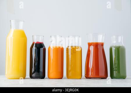 Glasflaschen mit Frucht- und Gemüsesäften in sauberer, minimaler Küche Stockfoto