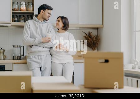 Junges Paar trinkt Kaffee in der Küche während des Umzugstages in einem neuen Zuhause Stockfoto