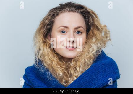 Junge blonde Frau im blauen Pullover schaut in die Kamera im Studio-Porträt Stockfoto