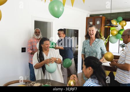 Sechs Gäste, die Partyplaner machen, in der Küche grüne Goldballons arrangieren, AR-Guide zeigt Girlande. Heim, Feier, Dekor, V Stockfoto