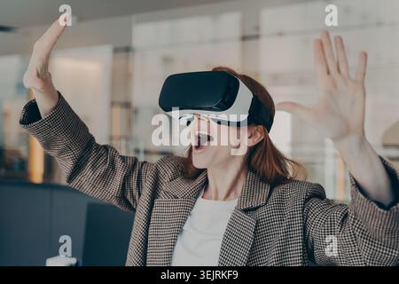 Geschäftsfrau verwendet Virtual-Reality-Headset und Gesten mit Händen in modernen Büros Stockfoto