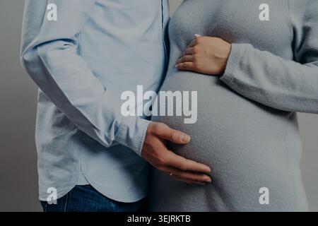 Das erwartende Paar hält den schwangeren Bauch sanft zusammen in der intimen Mutterschaft nah heran Stockfoto