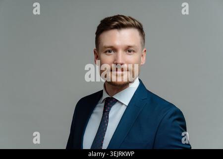 Studio-Aufnahme eines ernsthaften bärtigen männlichen Managers in formeller Kleidung blickt direkt auf Kamerapositionen vor grauem Hintergrund Stockfoto