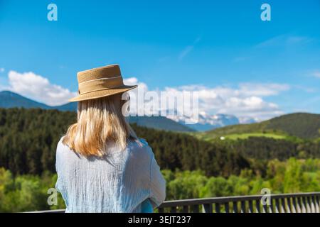 Junge Frau mit Strohhut, die einen Panoramablick auf die katalanischen Pyrenäen genießt Stockfoto
