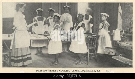 Preston Street Kochkurs, Louisville, K.Y, 1910. Afroamerikanische Kinder lernen kochen, möglicherweise im Rahmen einer Ausbildung für den Hausdienst. Mädchen mit Schürzen, Mützen und Ärmeln aus der Nähschule. Der Raum, der für diese Klasse genutzt wurde, wurde von Seminarstudenten gebaut, unterstützt von farbigen Jungen. Stockfoto