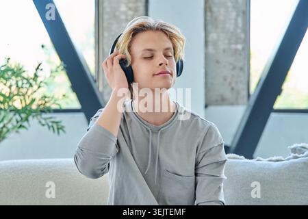 Junger Mann, der zu Hause Musik über Kopfhörer hört Stockfoto