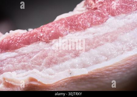 Ein Makrofoto von roher Haut auf dem Schweinebauch hebt das frische rosa mageres Fleisch und die reichhaltigen weißen Fettschichten hervor. Es fängt perfekt hochwertige Fleischqualität ein. Stockfoto