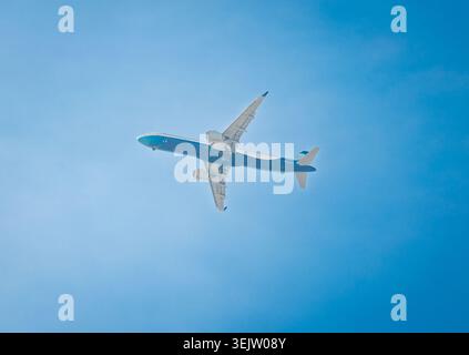 Passagierflugzeug, das an einem hellen sonnigen Tag hoch in klarem blauem Himmel fliegt Stockfoto