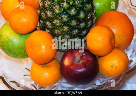 Eine Schüssel Obst auf einem Tisch, gesunde Nahrung, Gesundheit und Fitness, Ananas, Äpfel, Mandarinen und Orangen. Hohe Qualität Stockfoto