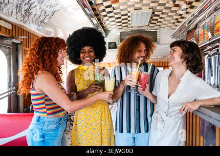 Multiethnische Gruppe junger glücklicher Freunde, die sich im Vintage Diner Burger House Restaurant verbünden - vielfältige Gruppe lächelnder Freunde, die erfrischenden smoot trinken Stockfoto