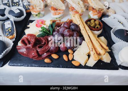 Käseplatte mit verschiedenen Aufschnitten, Trauben, Mandeln und Brotstäbchen Stockfoto