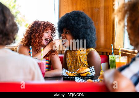 Multiethnische Gruppe junger glücklicher Freunde, die sich im Vintage-Diner-Burger-House-Restaurant zusammenschließen - junge multiethnische Freunde, die Fastfood-Dur essen Stockfoto