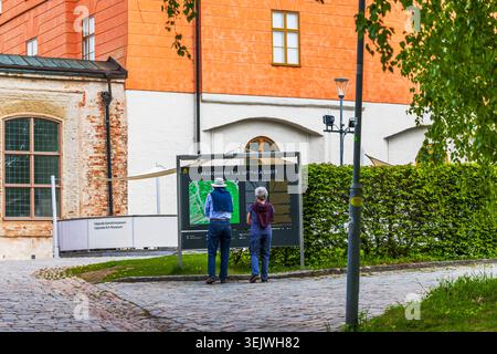 Nahaufnahme des Königspalastes in Uppsala mit Touristen, die eine Informationstafel in der Nähe des Eingangs lesen. Schweden. Uppsala. Stockfoto
