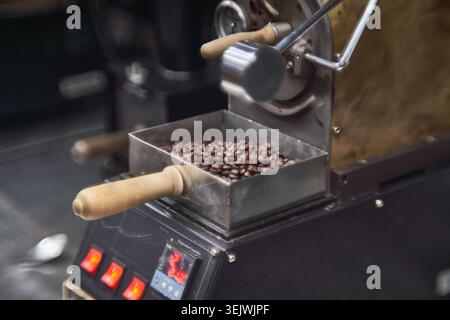 Von frisch gerösteten Bohnen in einer kleinen Maschine bis hin zu einem erfrischenden Glas eisgekühlten Americano – diese Bilder zeigen die Kunst der Herstellung von Premium-Kaffee. Stockfoto