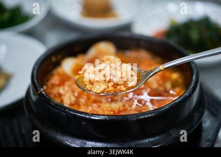 Sundubu-jjigae ist ein würziger koreanischer, weicher Tofu-Eintopf, der in einem heißen Töpfertopf serviert wird. Der zarte Tofu und die herzhafte rote Chili-Brühe sorgen für einen herzhaften Geschmack. Stockfoto