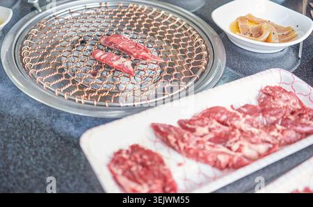 Hochwertiges Hanwoo-Rindfleisch wird über heißer Holzkohle auf einem Kupfergitter gegrillt. Dieses authentische koreanische Barbecue hebt zartes, marmoriertes Fleisch und herzhafte Aromen hervor. Stockfoto