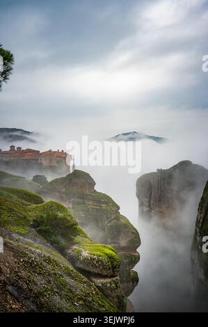 Das heilige Kloster von Varlaam in Meteora Felsen, erscheint durch die Wolken, Thessalien, Griechenland Stockfoto