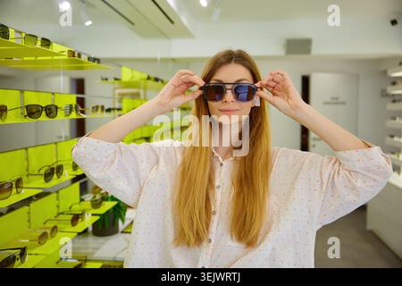 Junge Frau, die stilvolle Sonnenbrillen in der Boutique präsentiert Stockfoto