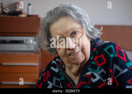 Lächelnde jüdische ältere Frau in ihrem Porträt aus den 80er Jahren in ihrem Schlafzimmer Stockfoto