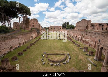 Weitwinkelblick auf das alte Stadion der Domitianischen Ruinen auf dem Palatin in Rom, Italien. Historische römische Architektur unter blauem Himmel mit Wolken Stockfoto