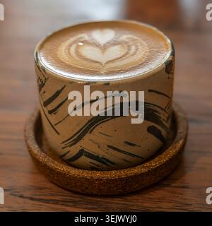 Eine moderne Kaffeetasse mit flachem weiß und einem komplizierten Design auf der Oberseite, serviert in einem Café auf der Insel Java, Indonesien Stockfoto