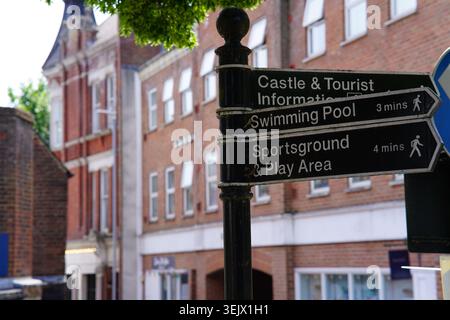 Schwarzes Wegweiser zum Schloss, Touristeninformationen, Schwimmbad und Sportplatz in der sonnigen britischen Stadtstraße. Stockfoto