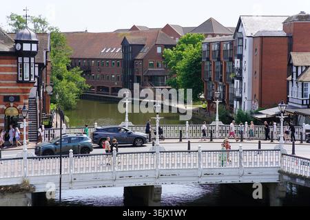 Weiße Brücke über den Fluss mit Menschen zu Fuß und Autos fahren durch die sonnige britische Stadt Uferpromenade mit modernen und historischen Gebäuden. Stockfoto