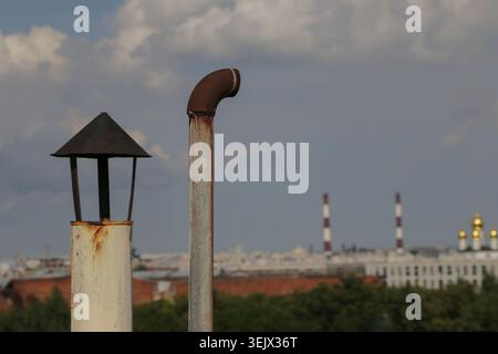 Metallrohr ist nach oben gebogen, verwittert und verschlissen. Weit entfernte Gebäude und Türme verblassen unter bedecktem Licht. Goldene Kuppeln leuchten sanft Stockfoto