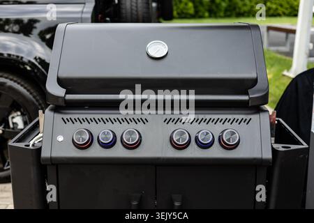 Eine detaillierte Aufnahme eines geschlossenen schwarzen Premium-Gasgrills mit Bedienfeld, Knöpfen und integriertem Deckelthermometer nach vorne. Ideal für die Anwendung Stockfoto