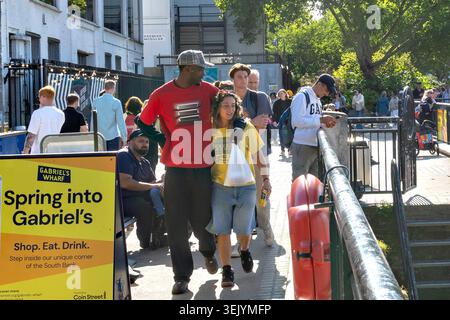 London, UK, 3. Mai 2026, Ein junges Paar, das gemeinsam an einem Schild für Gabriel's Wharf entlang der South Bank in London vorbeiläuft. Stockfoto