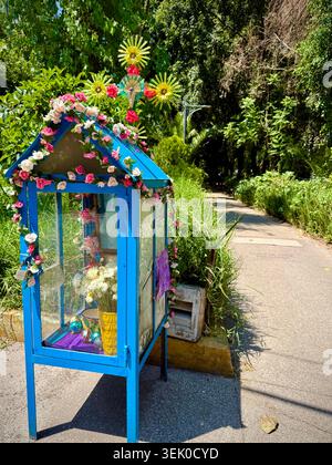 Ein kleiner, mit Blumen geschmückter Straßenschrein neben dem grünen Fußgängerweg auf der Avenida Amsterdam in Hipódromo Condesa, Mexiko-Stadt, spiegelt den alltäglichen Glauben und die populäre mexikanische Kultur wider Stockfoto