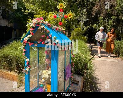 Ein kleiner, mit Blumen geschmückter Straßenschrein neben dem grünen Fußgängerweg auf der Avenida Amsterdam in Hipódromo Condesa, Mexiko-Stadt, spiegelt den alltäglichen Glauben und die populäre mexikanische Kultur wider Stockfoto