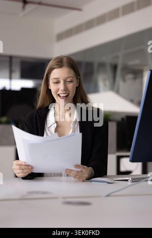 Geschäftsfrau fühlt sich beim Lesen von Dokumenten angenehm überrascht oder aufgeregt Stockfoto