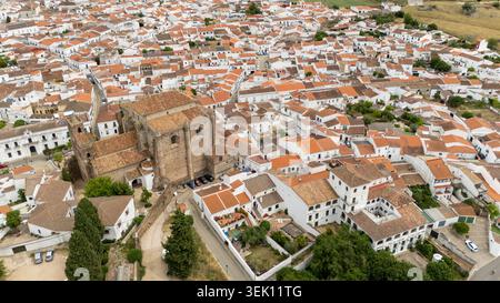 Aus der Vogelperspektive zeigt die historische Kirche und traditionelle weiße Häuser mit Lehmdächern in Cazalla de la Sierra, Andalusien, Spanien Stockfoto