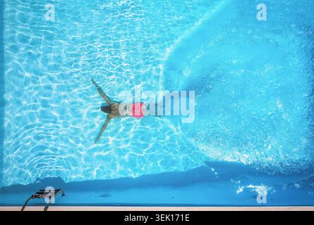 Von oben nach unten blickt man auf einen Mann, der in einem Swimmingpool taucht Stockfoto