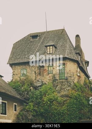 Melk, Österreich - 29.09.2021: Rustikales Berghaus mit verwitterten Holzschindeln und grünem Laub auf einem zerklüfteten Steinfundament Stockfoto
