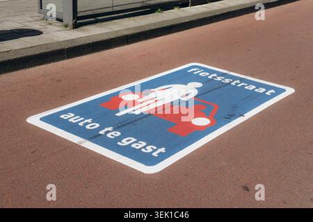 Amsterdam, Niederlande - 19. April 2026: Niederländische Straßenmarkierung „Fietsstraat Auto te gast“ auf Asphalt in Amsterdam, die Prio anzeigt Stockfoto
