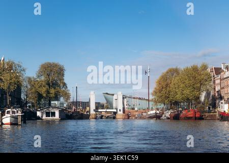 Amsterdam, Niederlande - 18. April 2026: Oosterdok-Kanal mit Booten und Oosterdoksebrug-Brücke in der Nähe des NEMO Science Museums in Amsterdam an einem sonnigen Frühling Stockfoto