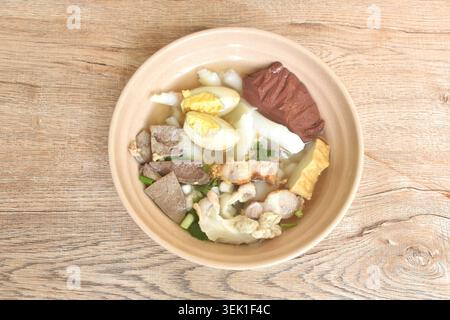 Große Reisnudeln hacken und knuspriges Schweinefleisch mit Organ belegt Ei in klarer Blutsuppe auf einer Schüssel Stockfoto