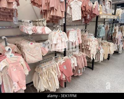 Ordentlich angeordnete Babykleidung auf Kleiderbügeln im hellen Supermarktbereich Stockfoto