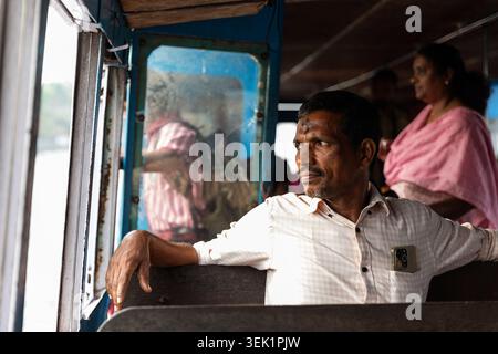 Passagiere, die in einer lokalen öffentlichen Fähre sitzen und durch die Backwaters in Alleppey (Alappuzha), Kerala, Indien navigieren. Stockfoto