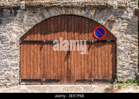 Alte Holzbogentür in traditioneller Steinmauer im Dorf Rupit, Katalonien, Spanien, mit rustikaler Handwerkskunst Stockfoto